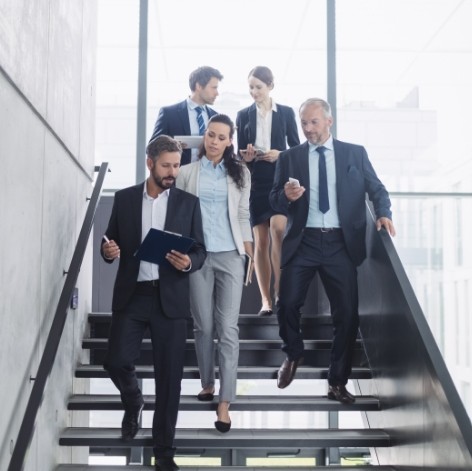 Equipo de profesionales de Sisole's colaborando en un entorno empresarial mientras descienden por las escaleras de la oficina.