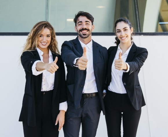 Equipo de profesionales de Sisole's sonriendo y mostrando aprobación con el pulgar arriba, reflejando confianza y compromiso con sus clientes.